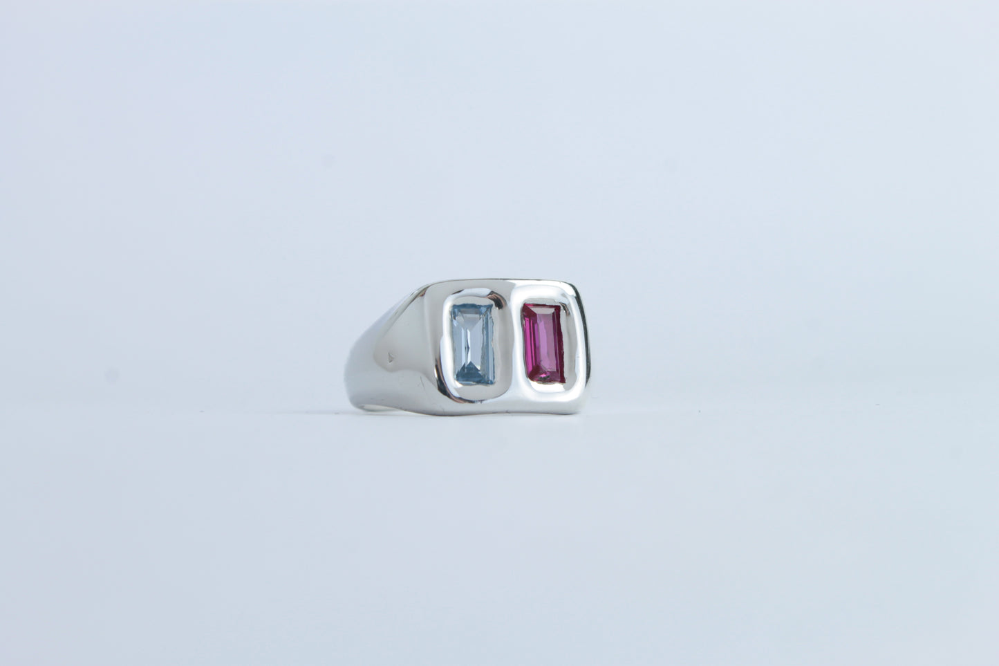 Silver ring with two gemstones on a light gray background