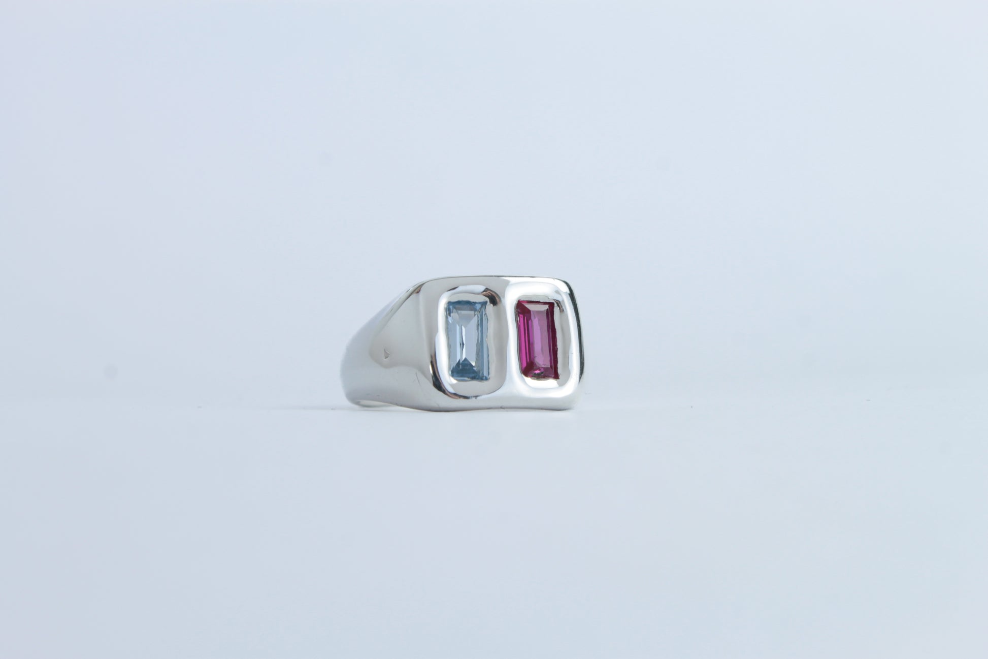 Silver ring with two gemstones on a light gray background