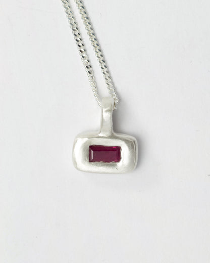 Ruby Pillow pendant necklace in sterling silver by Meg Henry featuring a horizontal lab ruby in a chunky satin-finished sculptural pendant on a curb chain.